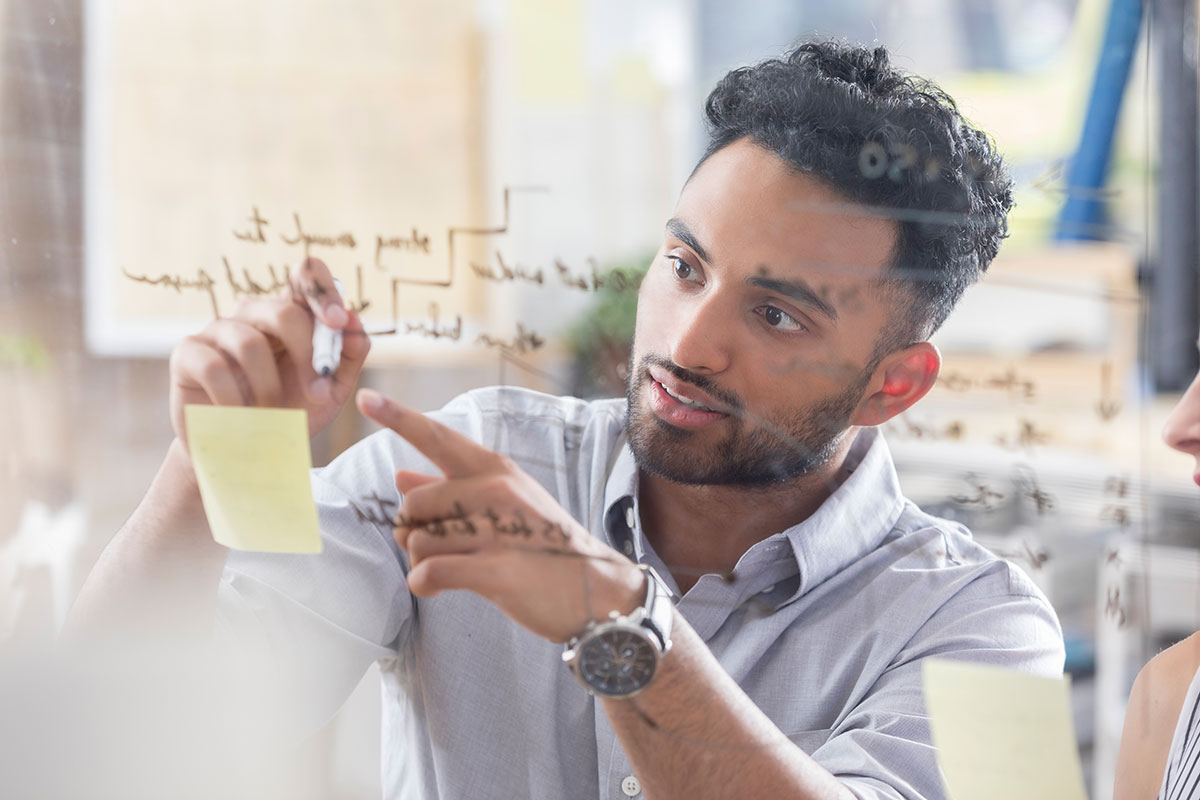 Man with sticky notes writing on glass