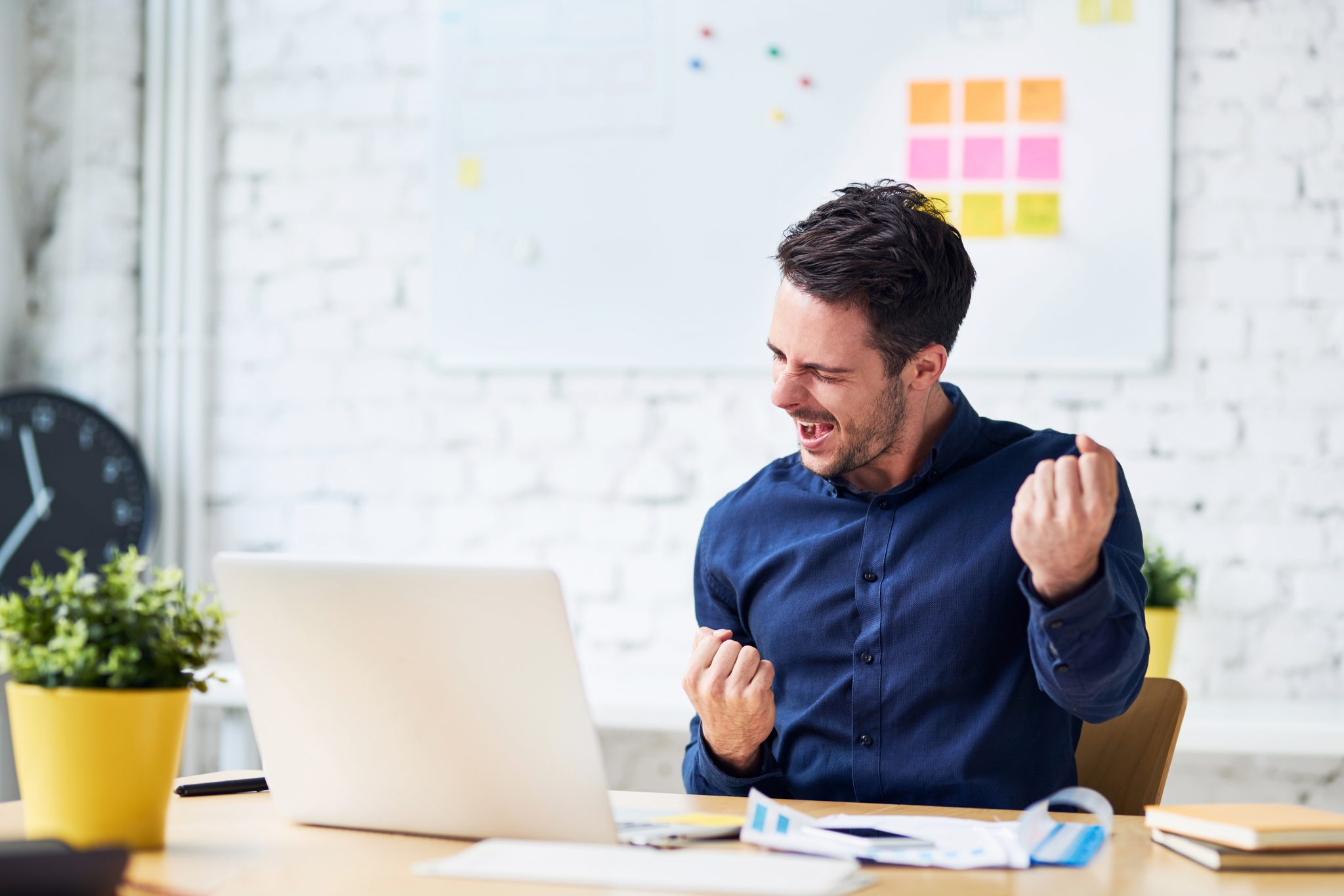 Man celebrating seated behind a laptop