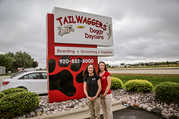 People standing in front of Tailwaggers Doggy Daycare sign