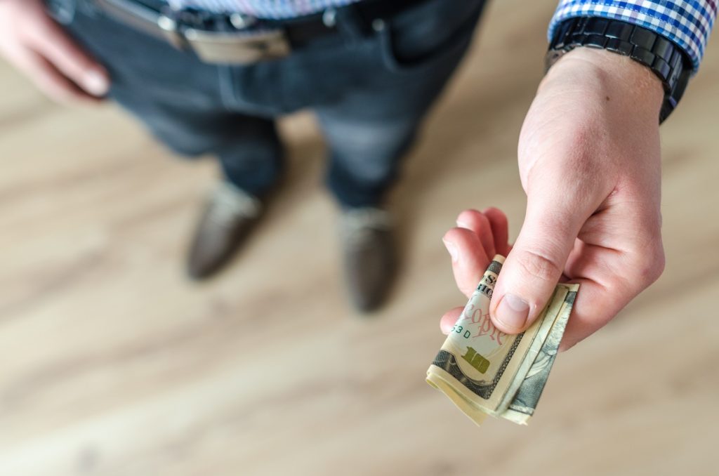 Man holding a folded ten dollar bill