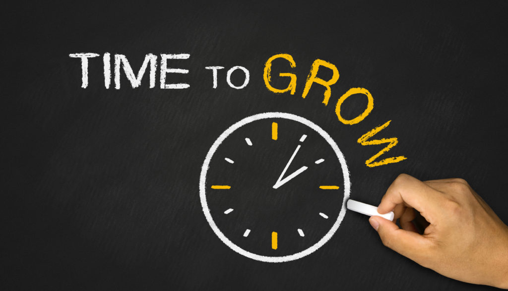 Person drawing a clock graphic that says Time to Grow