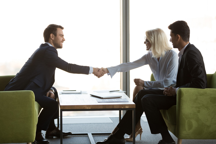 Friendly female and male business partners shaking hands, respect concept