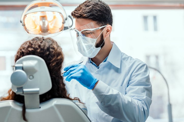 Dentist working in dental clinic with patient in the chair.