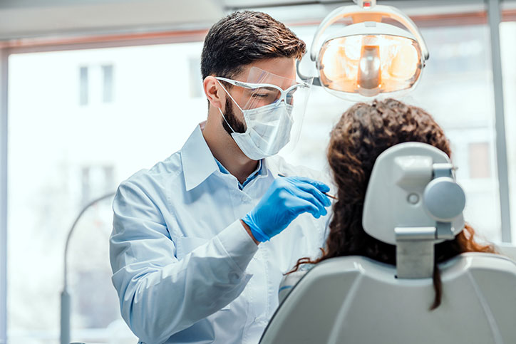 A dental cleaning wearing a mask and face shield