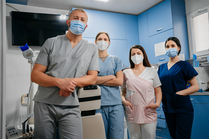 A dentist and dental assistants wearing medical masks
