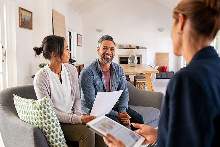 A smiling couple talking with a business professional